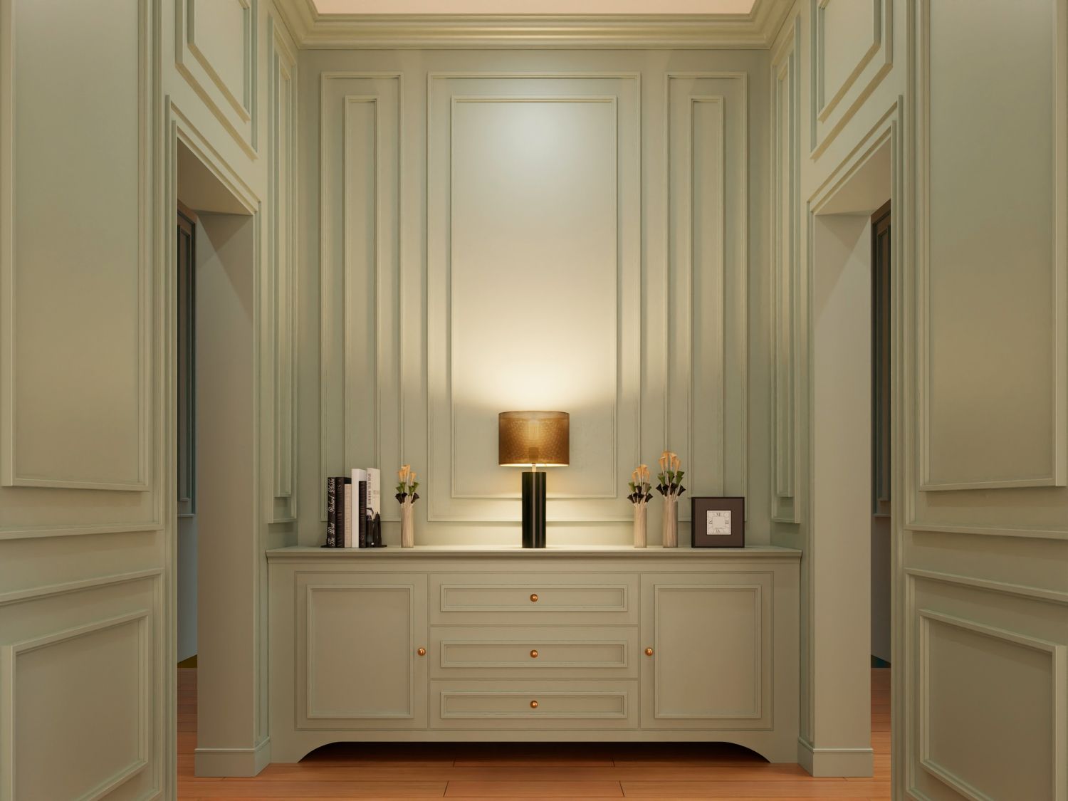 Elegant interior with a light green, paneled wall and a sideboard. A lamp softly illuminates books, framed art, and flowers, creating a serene atmosphere.