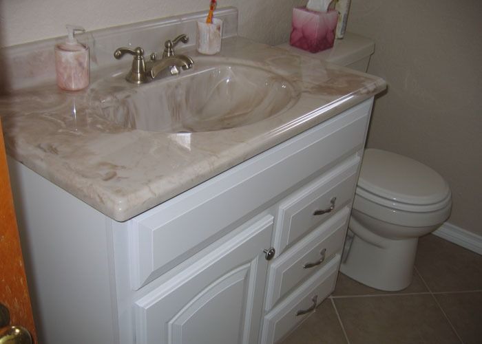 Marble sink installed sloping into a toilet, with a toothbrush holder and soap dispenser on the counter, creating a humorous tone.